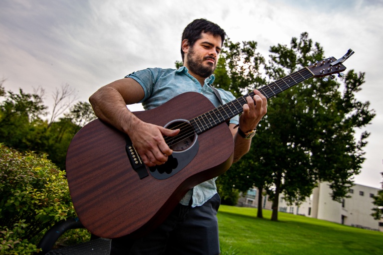 A man in a blue shirt playing a guitar.