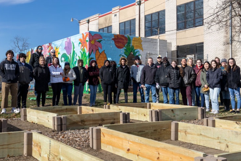 Philosophy students and faculty standing around garden beds at the Carver Community Center.