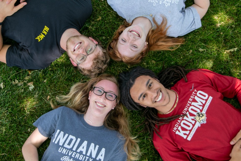  Four students lay on the ground next to each other.
