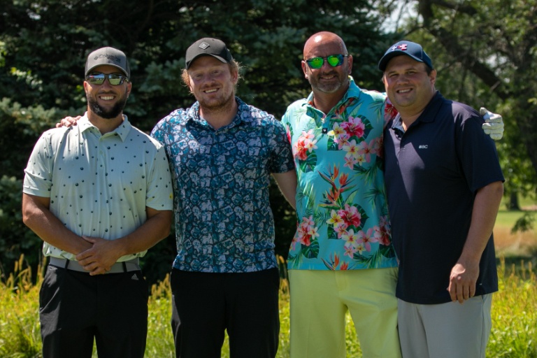 Group of men in golf attire smiling at camera.