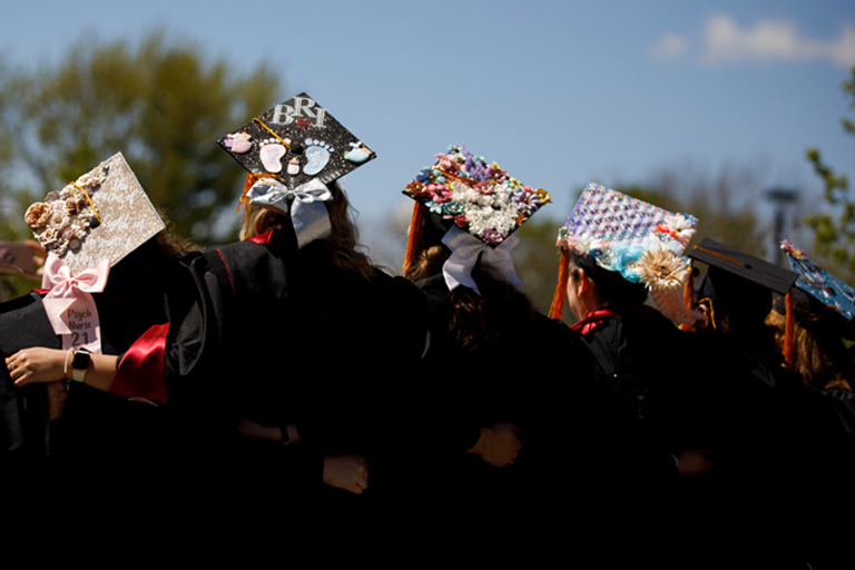 Graduates with decorated caps hug each other