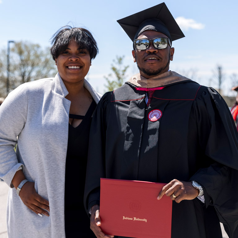 A smiling woman stands for a photo with a male IUK graduate