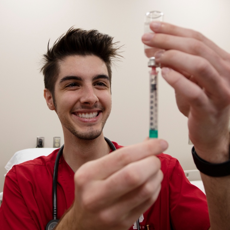 Student holding syringe in clinical lab.