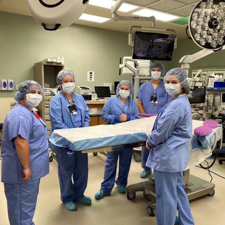 Five students standing in an operating room in full scrubs.