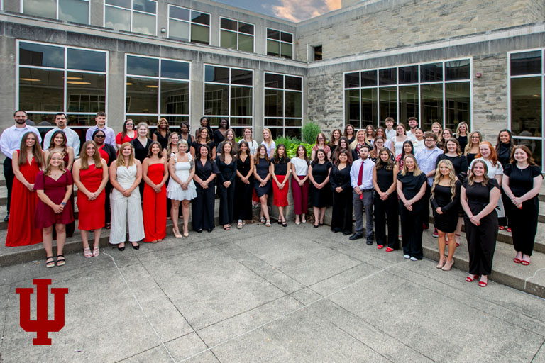 A group picture of three rows of people in a courtyard.