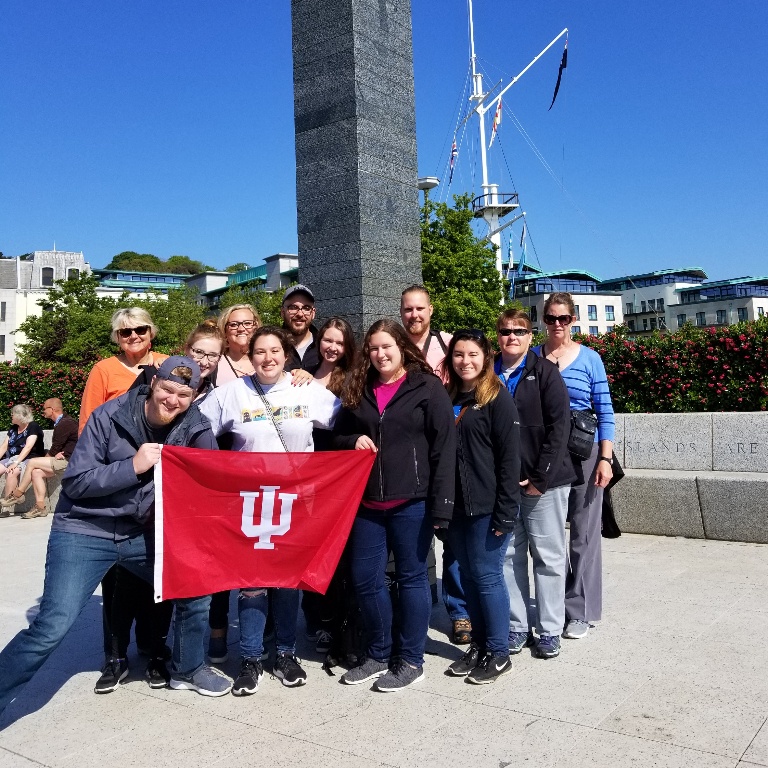 Students holding an IU banner in front of a statue. 